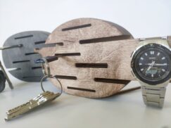 A lifestyle shot showing a hand placing a key on one of the hooks of the wall-mounted organizer.