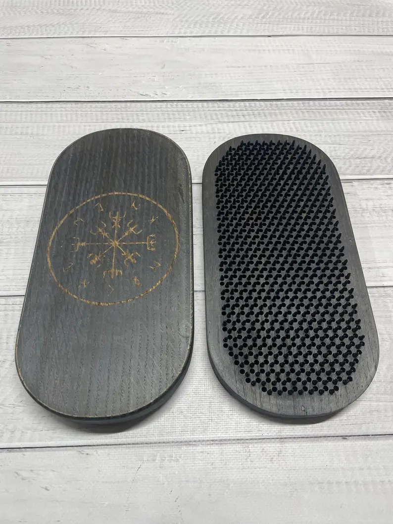 The sadhu board in a hand, demonstrating its weight and portability.