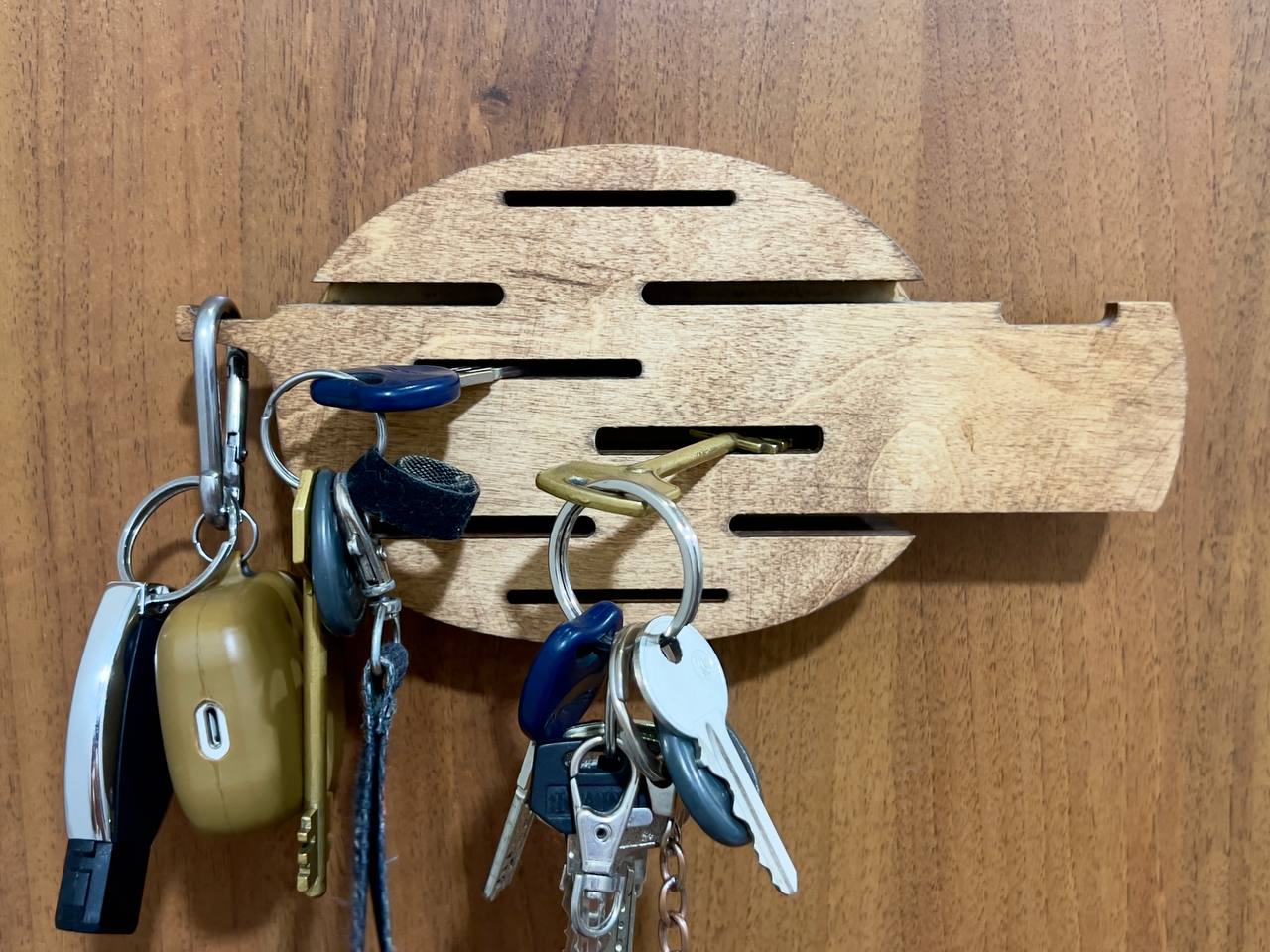 A lifestyle shot showing a hand placing a key on one of the hooks of the wall-mounted organizer.