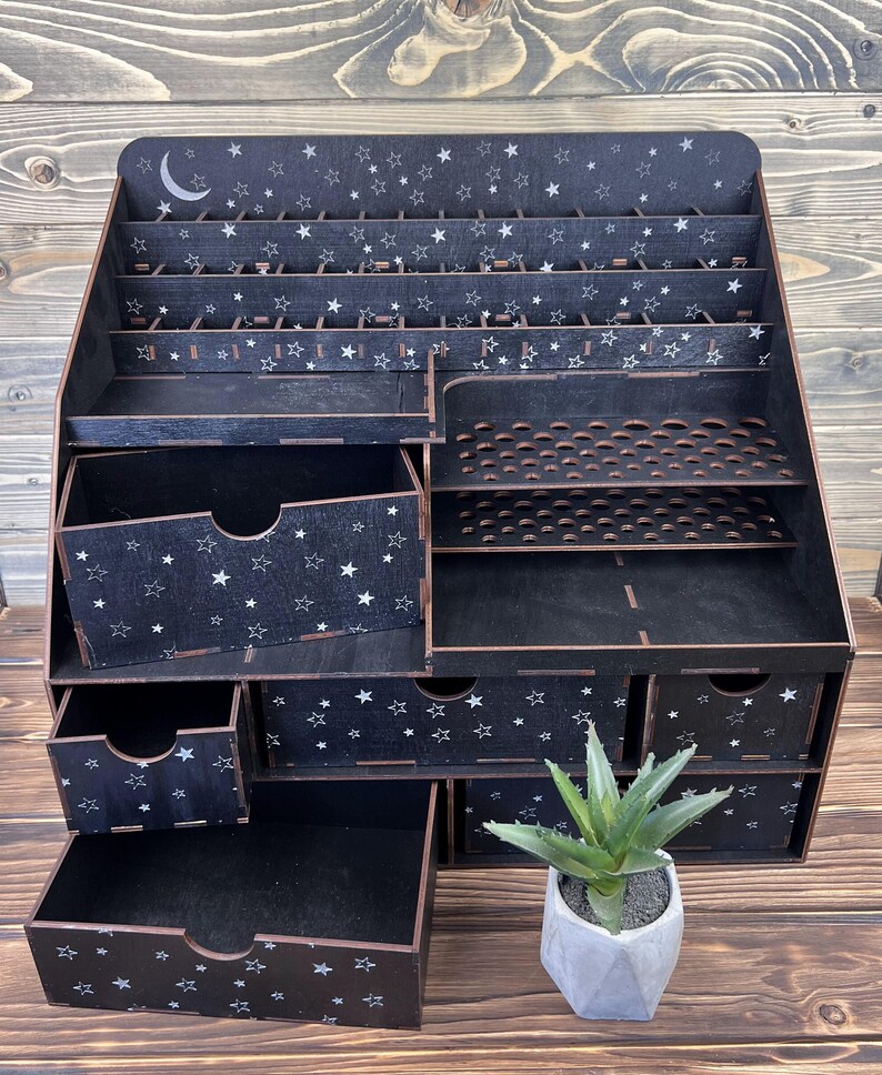 A view of the black "Eve" cosmetics holder, filled with cosmetics, on a vanity table.