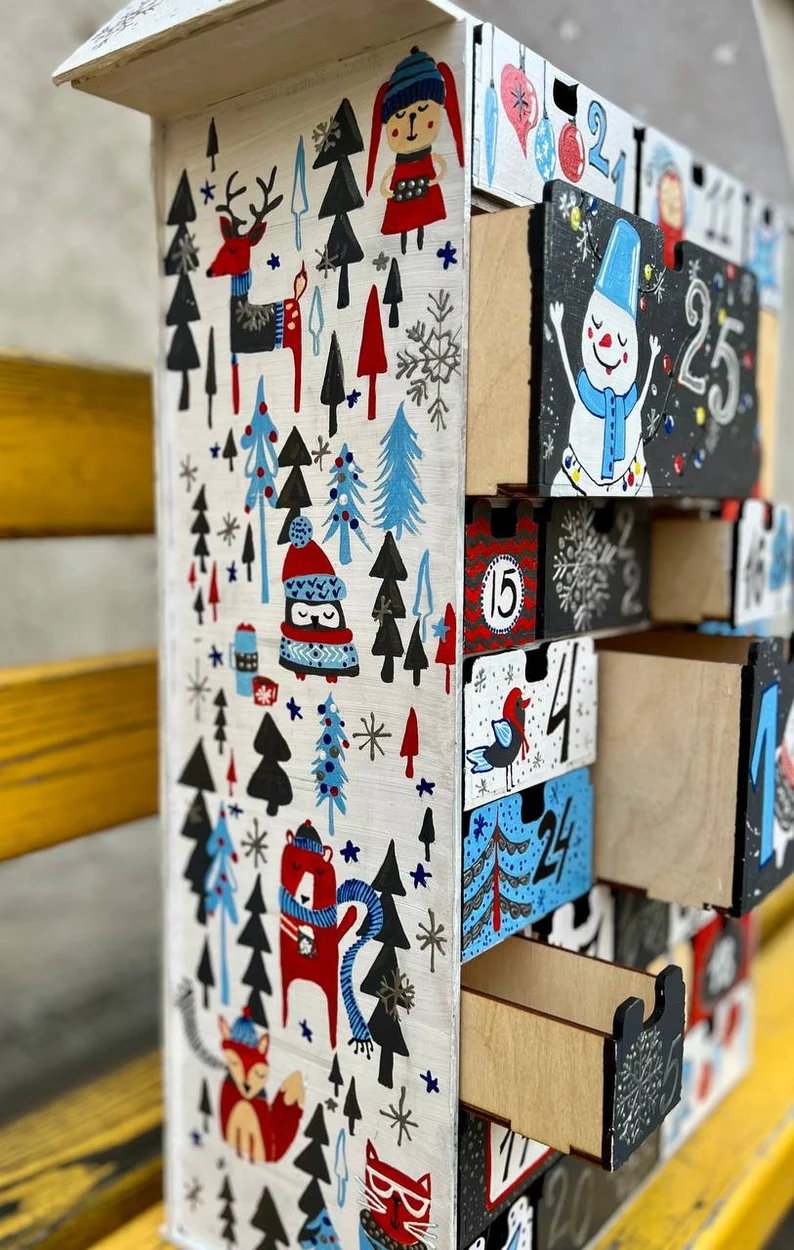 The advent calendar styled on a mantelpiece, surrounded by other holiday decorations like stockings and garlands.