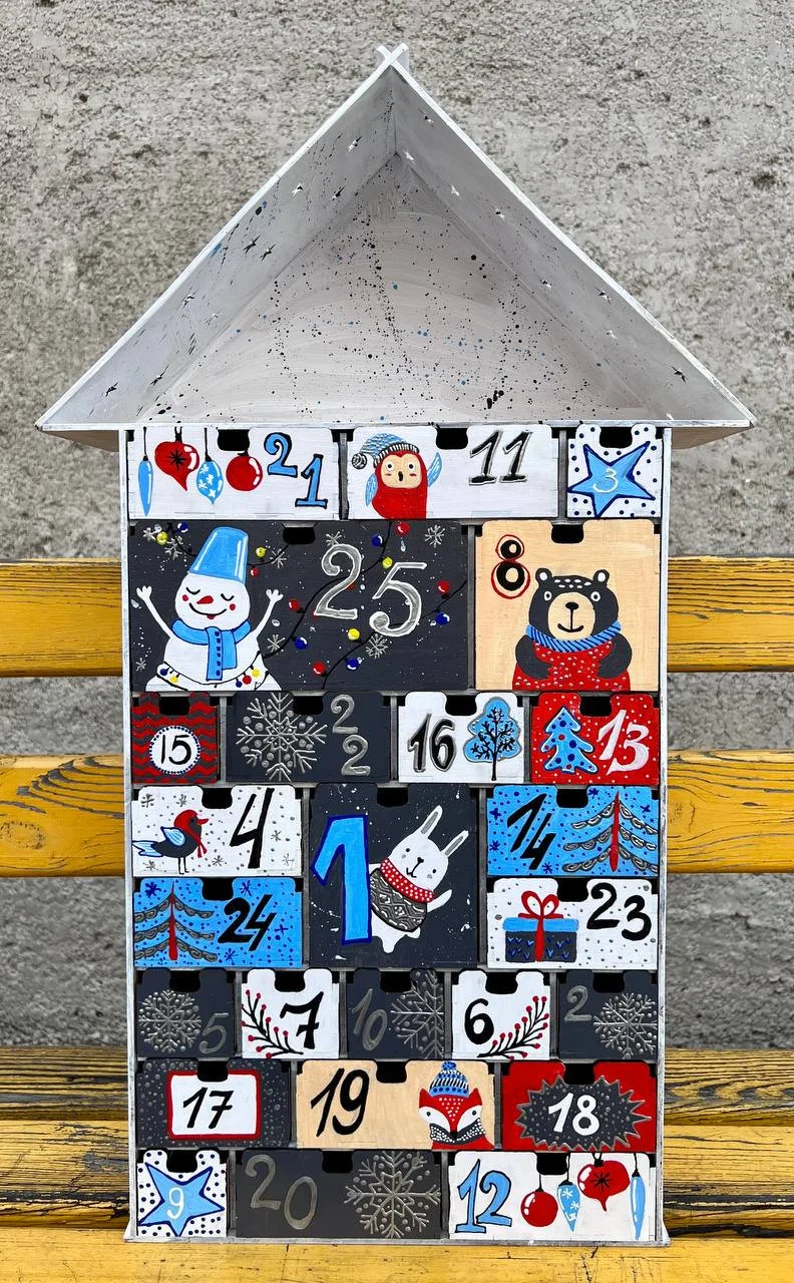 A full view of the hand-painted wooden advent calendar, showing all 24 numbered drawers and its festive decorative elements.
