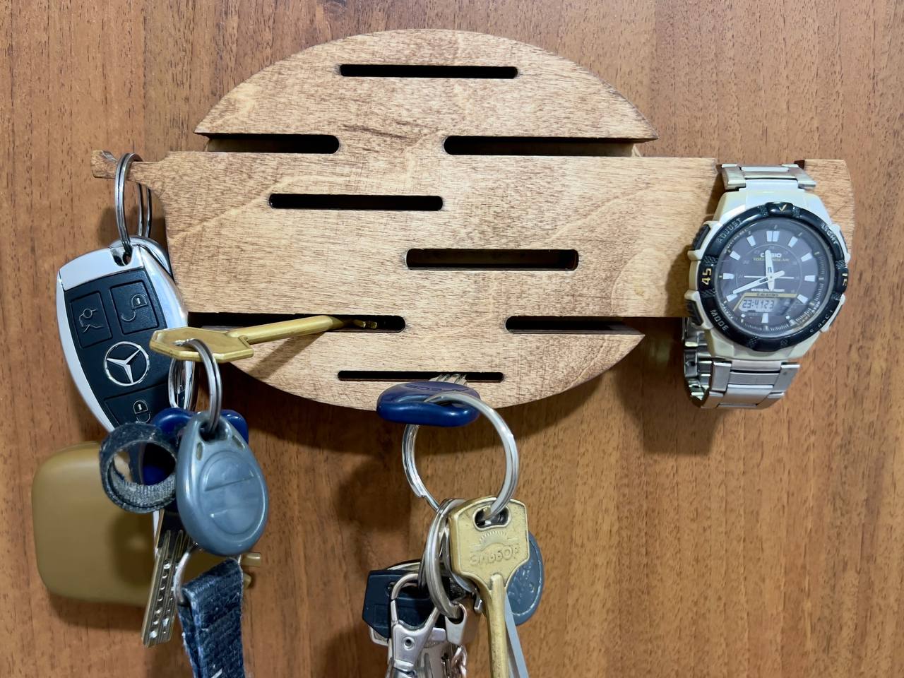 A side-profile shot of the wooden key holder, showing its thin, sleek construction and the smooth, natural wood grain.