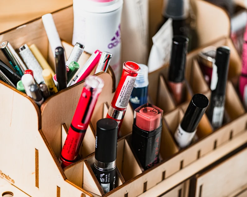 A photo of a hand placing a lipstick into one of the compartments, showing the ease of use.