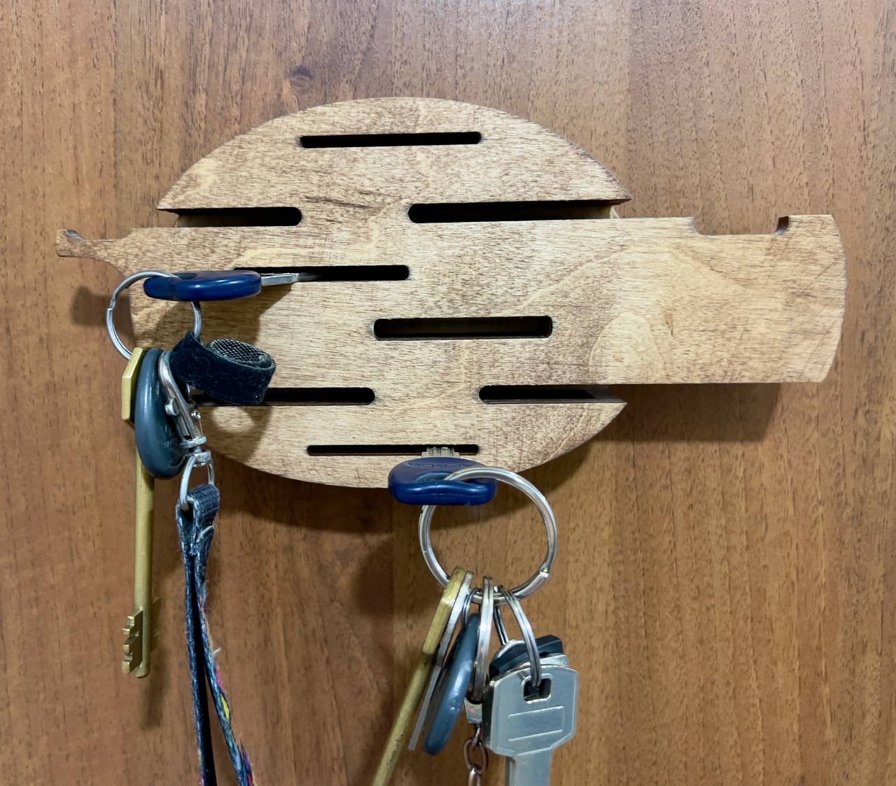 A close-up shot of the key holder on a textured wall, focusing on the quality of the wood and the smooth finish.