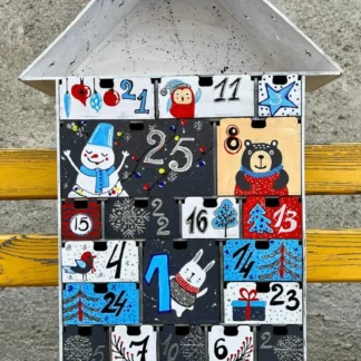 A flat lay image of the advent calendar with some small gifts or candies scattered around it.