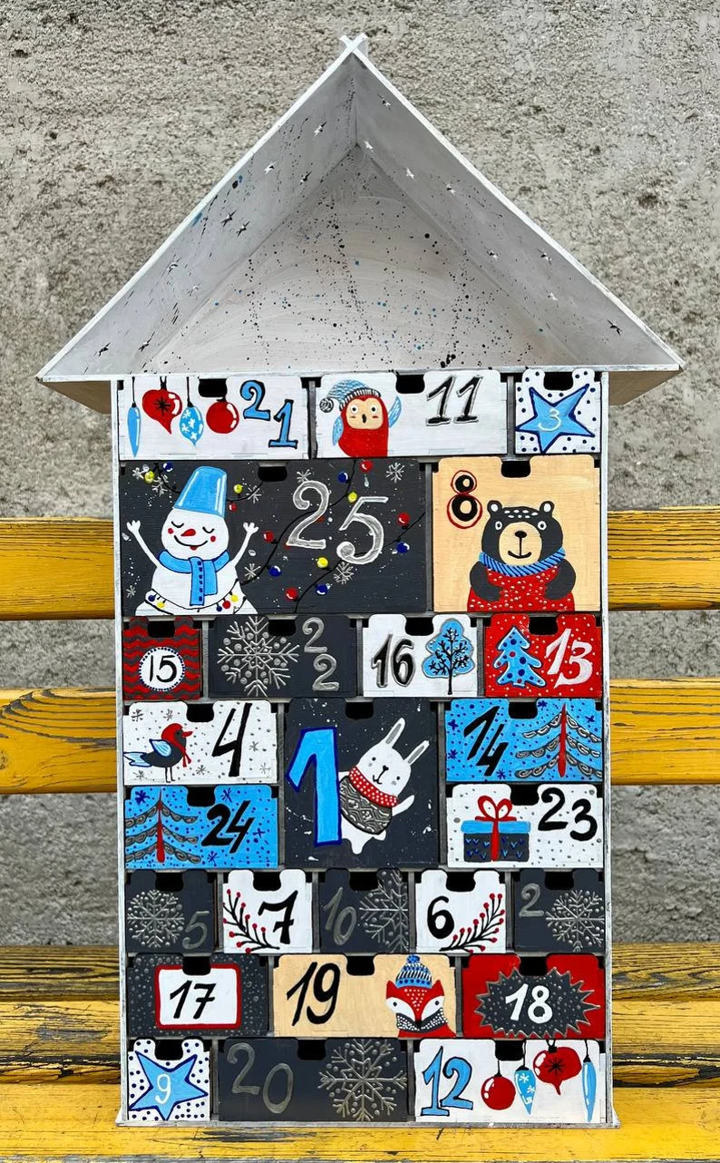 A flat lay image of the advent calendar with some small gifts or candies scattered around it.