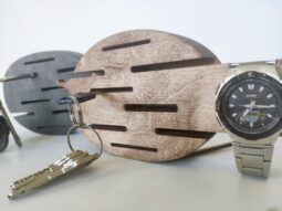 A lifestyle shot showing a hand placing a key on one of the hooks of the wall-mounted organizer.