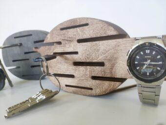 A lifestyle shot showing a hand placing a key on one of the hooks of the wall-mounted organizer.