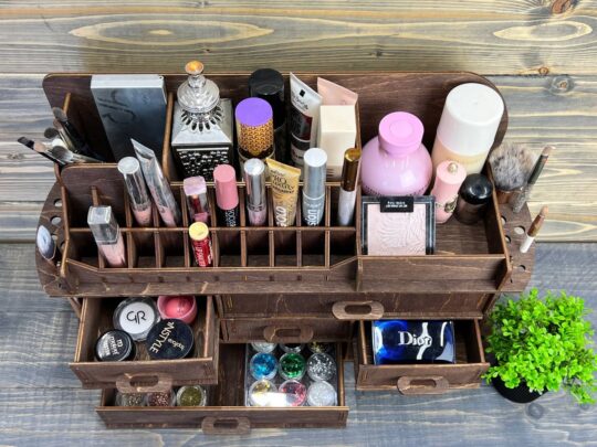 A beautifully styled photo of the ultimate wooden makeup organizer on a countertop, filled with a variety of makeup brushes, palettes, and cosmetic bottles.
