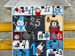 A flat lay image of the advent calendar with some small gifts or candies scattered around it.