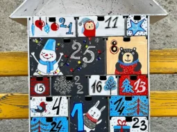 A flat lay image of the advent calendar with some small gifts or candies scattered around it.