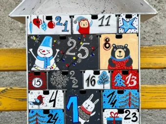 A flat lay image of the advent calendar with some small gifts or candies scattered around it.